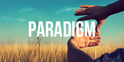 Photo consists of a field of wheat crops. A person's arms can be seen to the right, reaching out to make a rectangle shape with their hands.